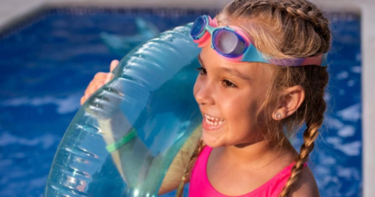 little girl with goggles holding pool floaty